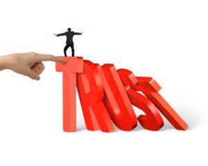 Man balancing on large letters that spell out trust, representing the domino effect of trust and trust in construction