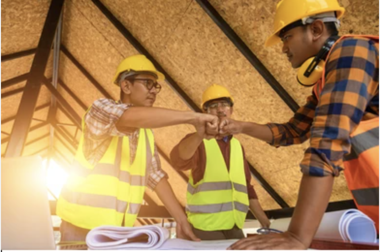 Construction workers bumping fists indicating independence and collaboration
