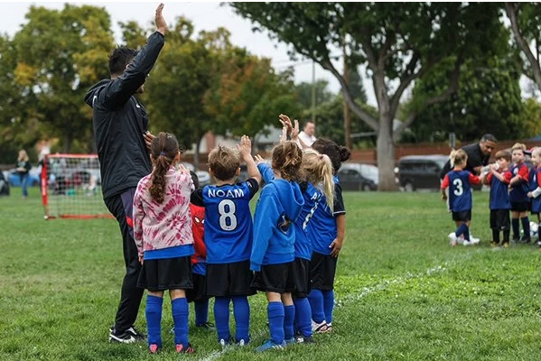 Young soccer players group around their coaches - Managing time