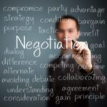 Man writing negotiation in white on a glass wall - Negotiation Strategies